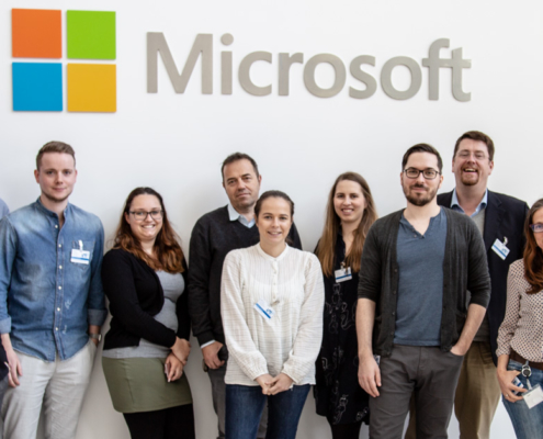 Teilnehmer des Paid-Social-Media-Workshops posieren unterhalb eines großen Microsoft-Logos.