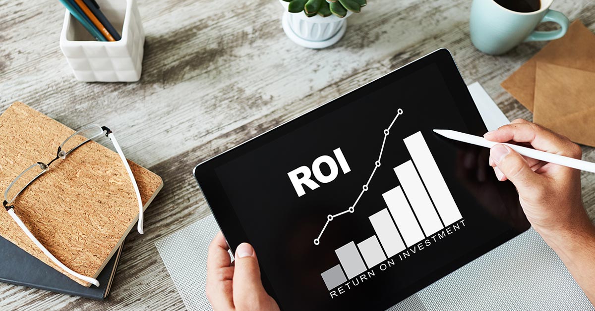 Eine Person hält ein Tablet in der Hand, auf dem ein Diagramm und "ROI - Return on Investment" steht.